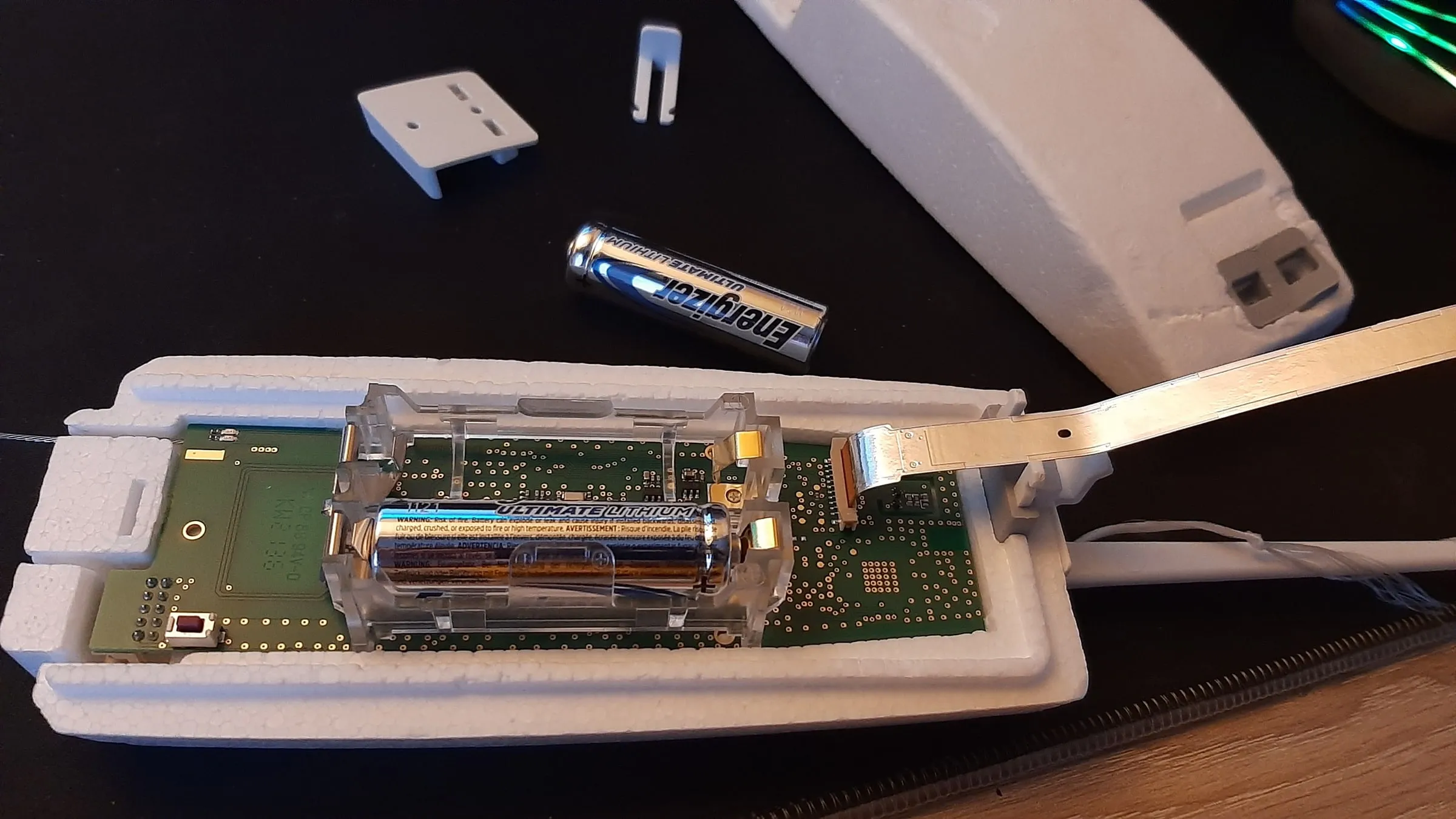 An open radiosonde on the table, with its board, battery and sensor