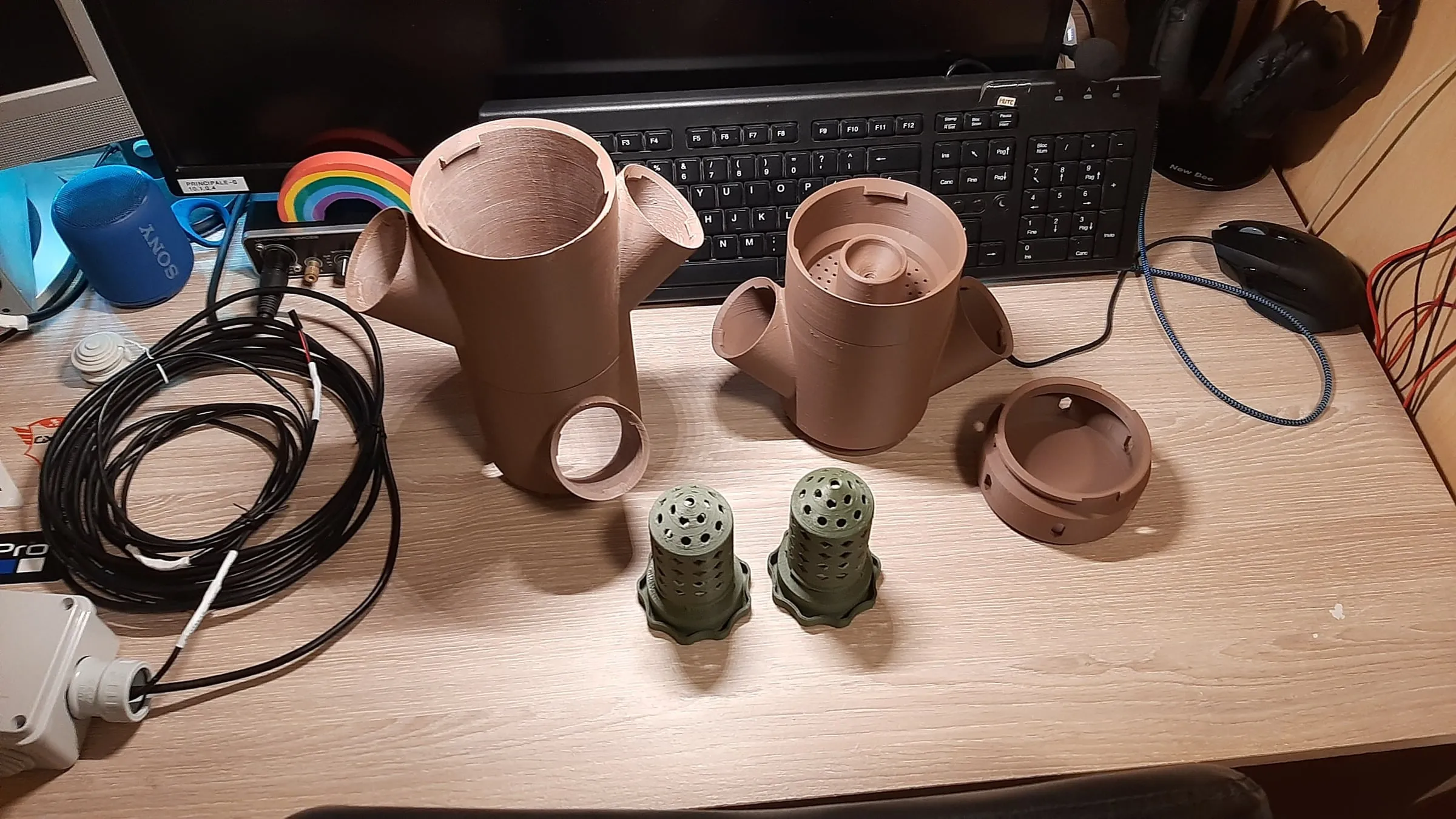 The first printed pieces of the tower on the desk: two brown modules and a few green pots full of holes
