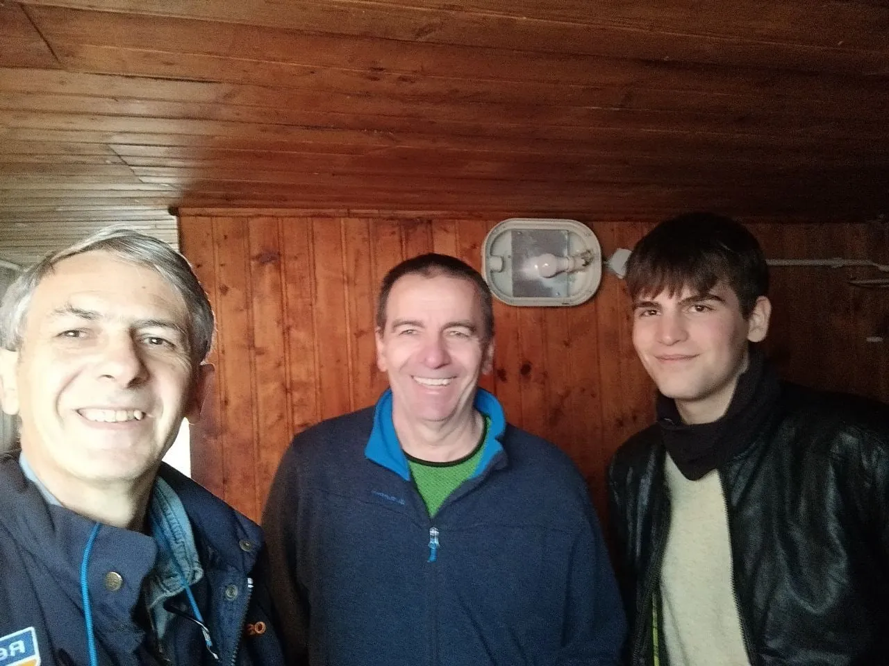 Ernesto, Alberto and Stefano smiling inside the hut on Monte Ucia