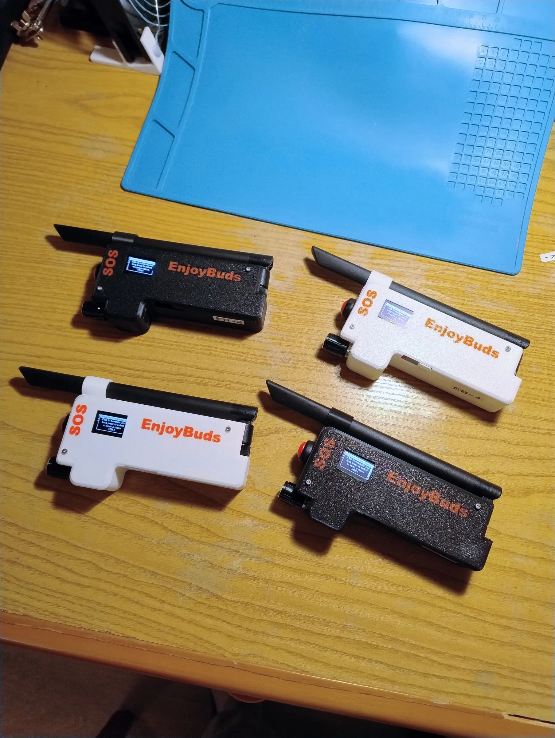 The four EnjoyBuds prototypes, two white and two black, on a workbench