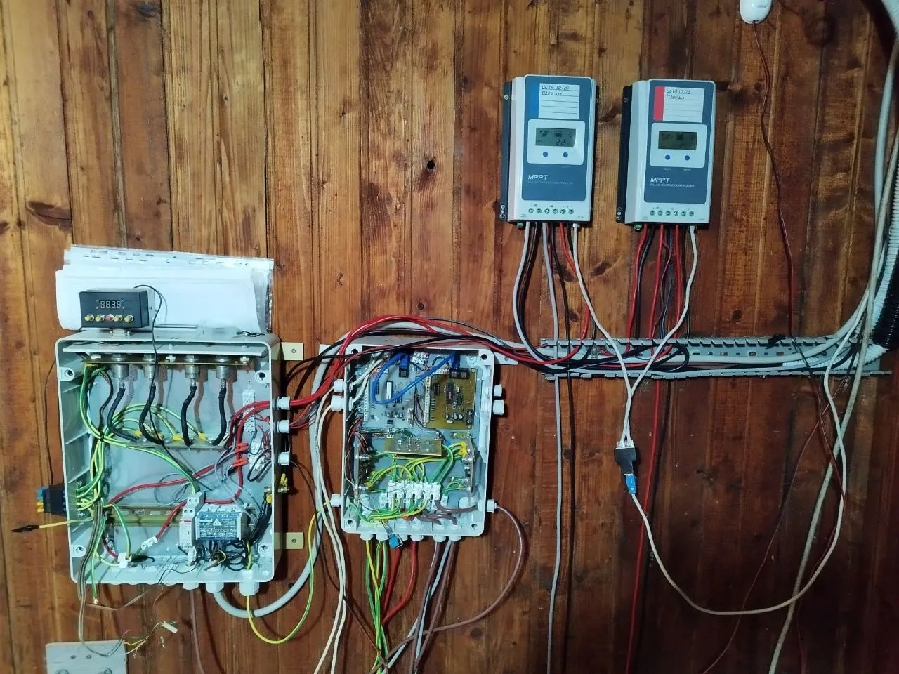 Two charge controllers and the remote control boxes fixed to the wooden wall of the hut
