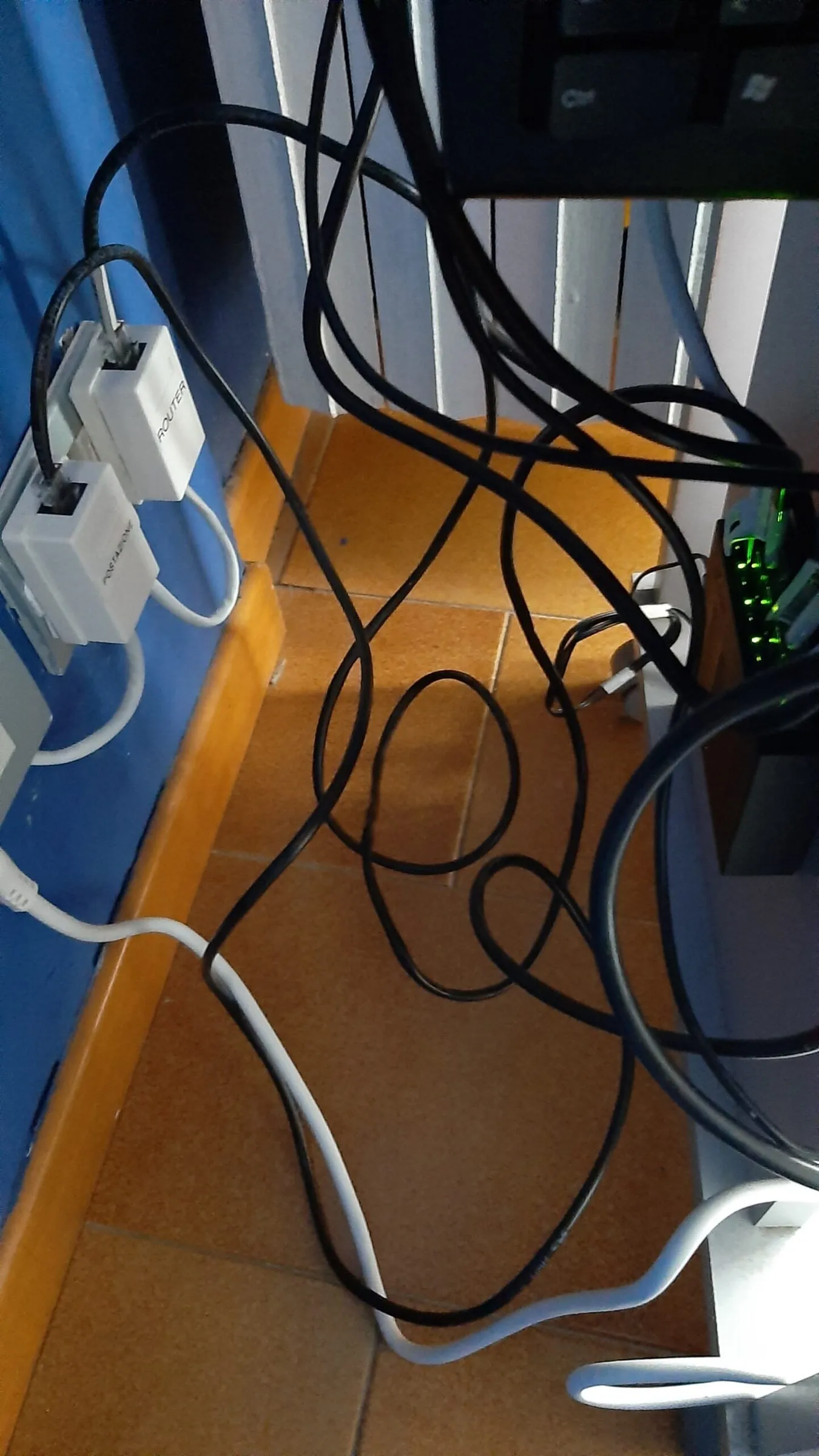 Il retro del mobiletto del primo server, con i cavi di rete e i due adattatori etichettati per il router