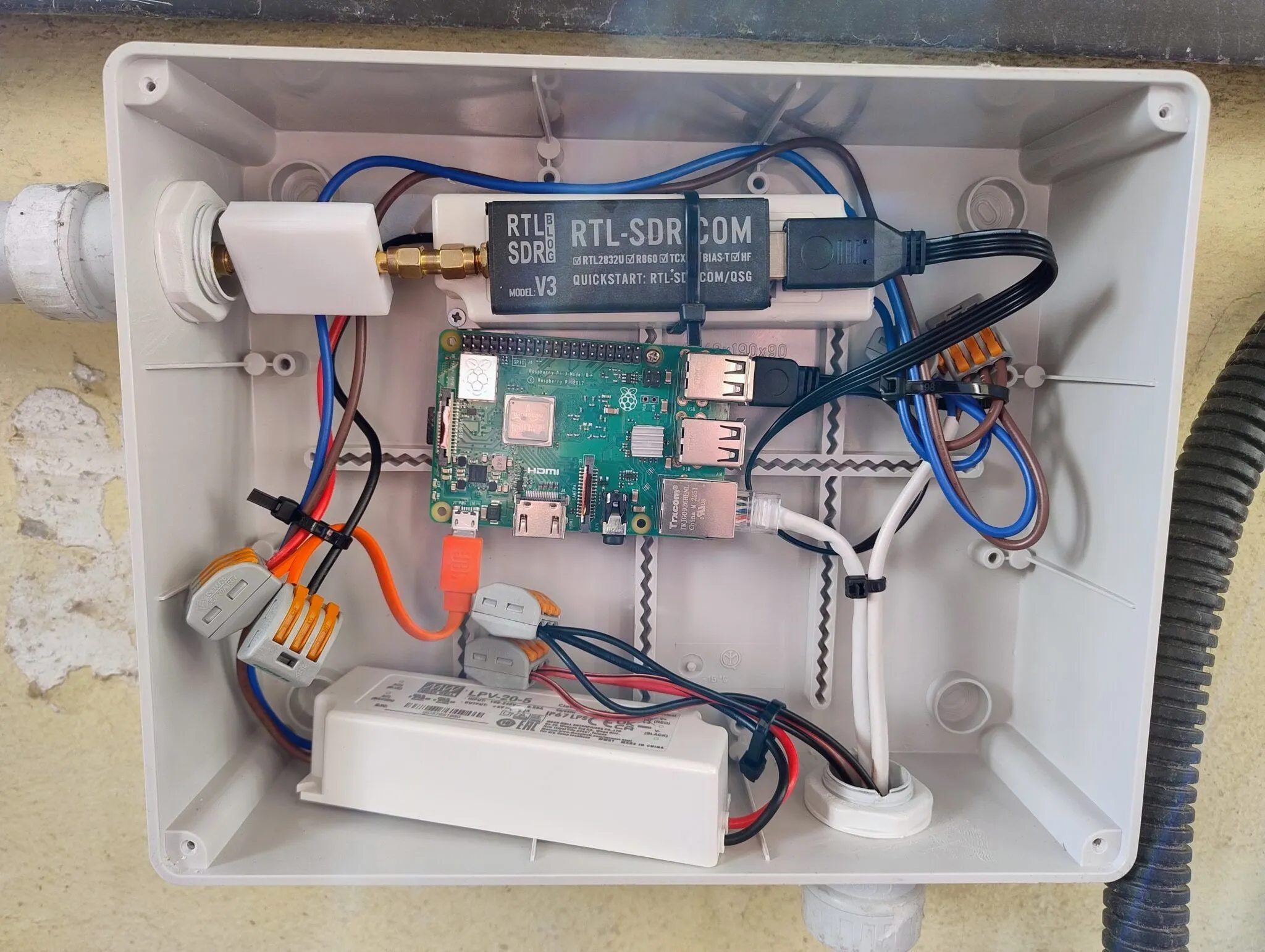 The open box: the SDR stick fixed above the Raspberry Pi, with the cables and the power supply underneath