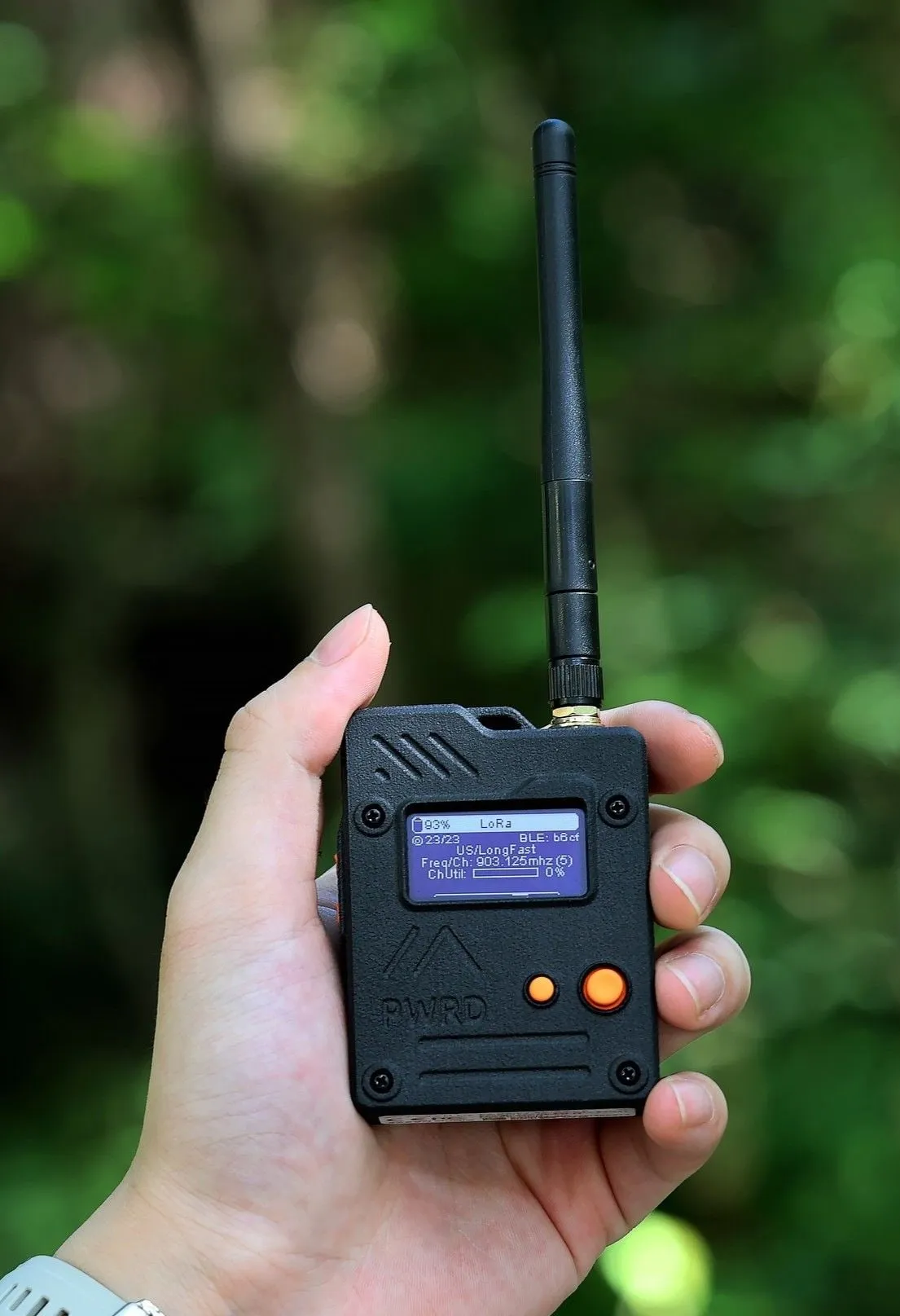 The device with the screen, black and switched on, held in a hand outdoors